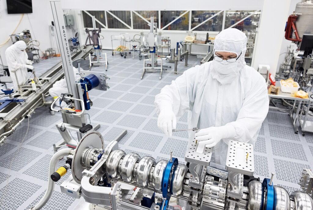 Workers in protective suits inside a semiconductor cleanroom factory